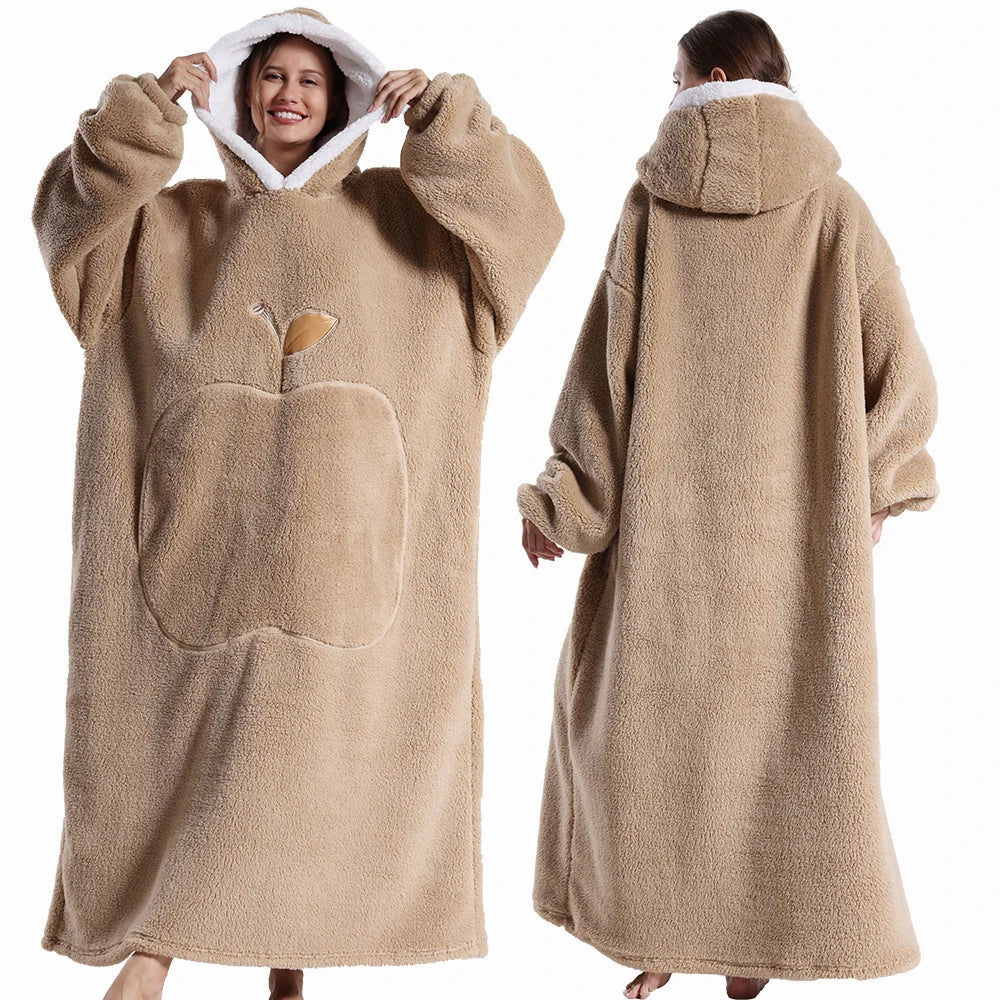 Deux vues d’une couverture-hoodie oversize beige en sherpa portée par une femme ; capuche doublée blanche et grande poche kangourou visible.