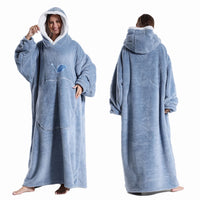 Deux vues d’une couverture-hoodie oversize bleue en sherpa portée par une femme ; capuche doublée blanche et grande poche kangourou visible.