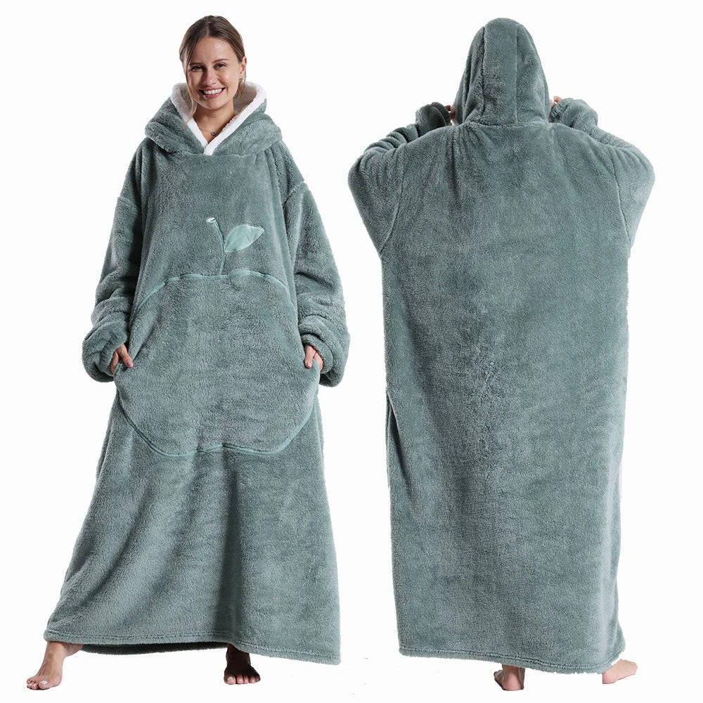 Deux vues d’une couverture-hoodie oversize verte en sherpa portée par une femme ; capuche doublée blanche et grande poche kangourou visible.
