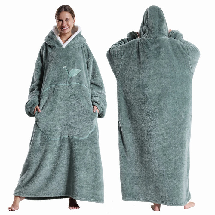 Deux vues d’une couverture-hoodie oversize verte en sherpa portée par une femme ; capuche doublée blanche et grande poche kangourou visible.